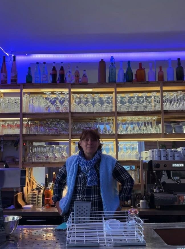 Isabelle Louis derrière le comptoir d'Au Bouchon by Isa, devant les étagères de verres